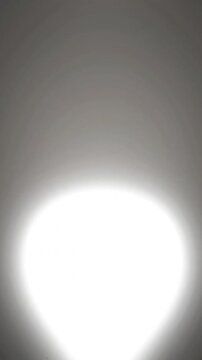 Bright glowing circular light flare expanding slowly within dark gray atmosphere captured in dynamic high resolution digital motion video clip
