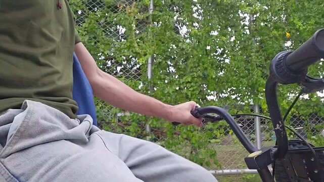 Close-up shot of an unidentified man riding a bicycle on a designated bike path in a lush public park, surrounded by greenery. Concept of a healthy lifestyle, outdoor exercise, and active living