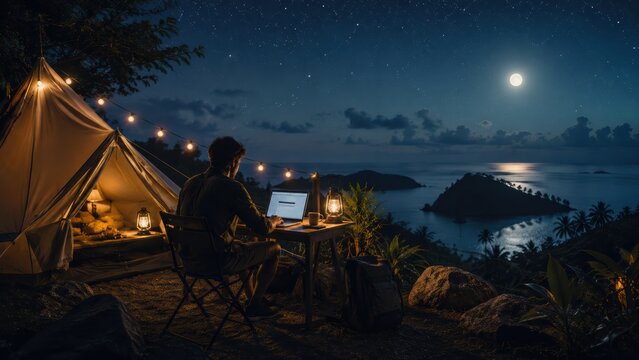  person works on a laptop beside a tent at night, illuminated by lanterns and string lights, overlooking a serene ocean view under a starry sky and full moon.