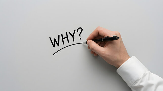 A hand writes the word why with a black pen on white paper