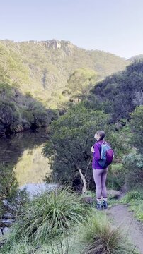 A girl stands on the edge of a ridge, overlooking the meandering river below, along the Werribee Gorge Circuit Walk, near Melbourne, Victoria, Australia.