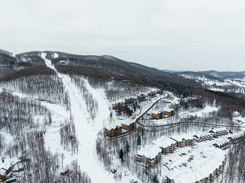 Aerial winter view of Bromont ski resort with snowy slopes, village and parking area in Quebec, Canada. g.