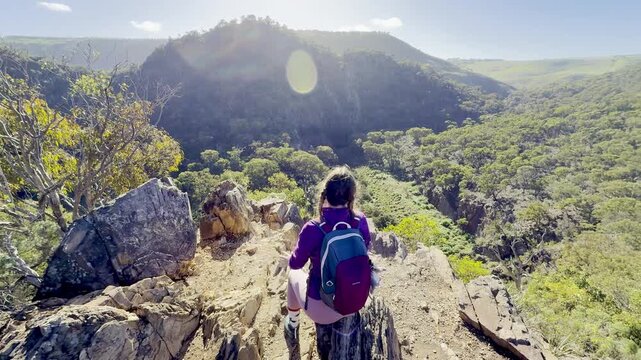 A girl sits on the edge of a ridge, overlooking the meandering river below, along the Werribee Gorge Circuit Walk, near Melbourne, Victoria, Australia.