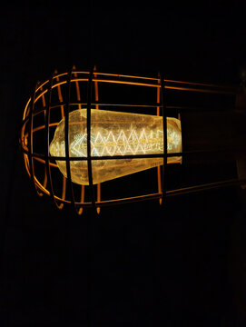 an incandescent light bulb enclosed in a vintage metal protective cage