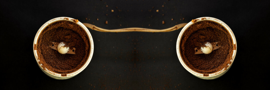 an electric blade coffee grinder filled with freshly ground dark roast coffee beans, featuring a spinning metal blade and a central safety button/post