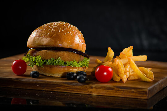 Delicious burger with fries and garnish presented on a wooden board in a restaurant setting