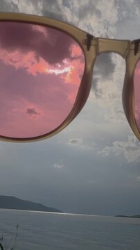 Cloudy Sky Seen Through Pink Sunglasses Beside the Water