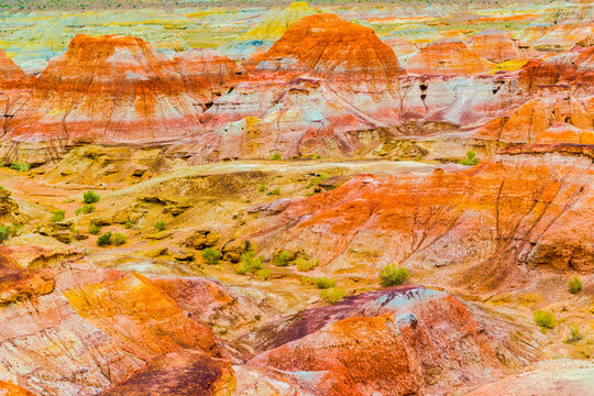 Spectacular colorful landforms at Wucai City in Xinjiang, China. Layers of red, yellow, orange and brown rocks form a dramatic Yardang desert landscape shaped by wind erosion in the vast and remote te