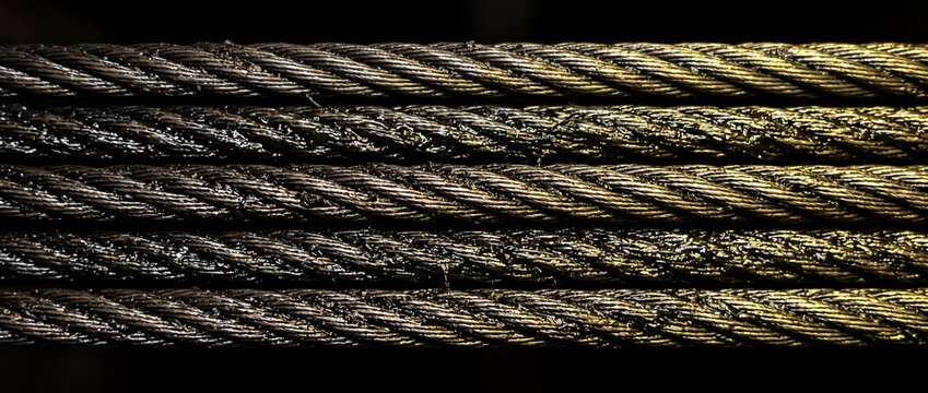Industrial steel wire rope cable consists of twisted metallic strands with oily coating for heavy lifting operations in construction site