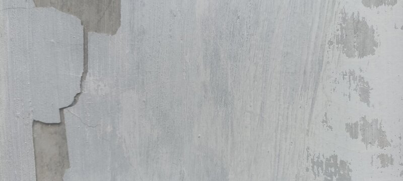 Chipped paint surface on light grey concrete wall texture with worn coating, useful background for urban decay, vintage layout, industrial design, and weathered backdrops