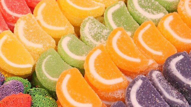 Colorful gummy candies in fruity slice shapes arranged in rows, close-up footage