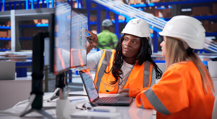 Two Warehouse Workers Using Laptop To Track Inventory