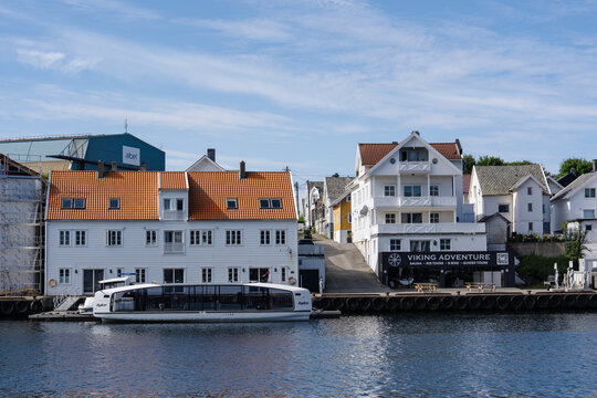 August 19, 2026, Haugesund, Norway - Waterfront view of traditional buildings, a Hyke tour boat, and a Viking Adventure business