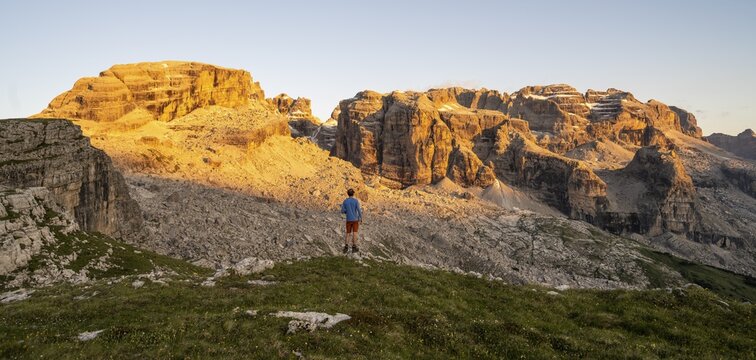 Mountaineer enjoying the view of rocky mountain peaks of the Brenta Mountains at sunset, Alpengl&uuml;hen, mountain landscape on the Grost&eacute; Plateau, Brenta, Parco Naturale Brenta-Adamello, Trentino, Italy