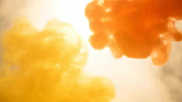 Two amorphous shapes, golden yellow and orange, float against a soft white background. The image has a soft and diffused, dreamy look