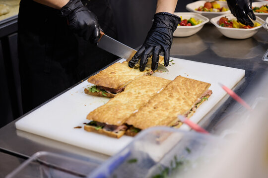 Chef Cutting Fresh Sandwiches on a Prep Counter