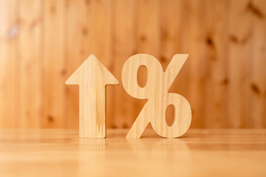 Interest rate hike and inflation percentage concept with wooden upward arrow and percent symbol on table against wood wall background for banking loan cost increase and financial yield growth.