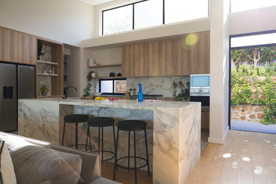 Marble kitchen island is anchoring bright modern kitchen with three black bar stools
