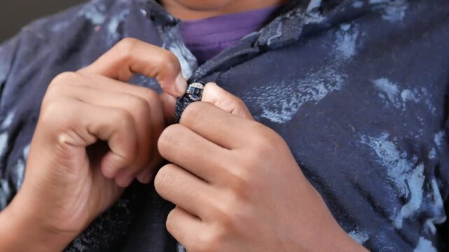 A close-up view of a person wearing a denim shirt, showcasing the texture and movement of the fabric as they button up