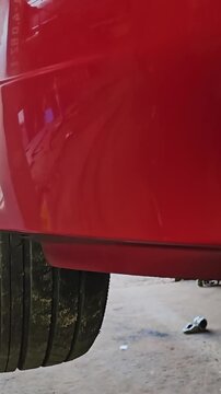 The red car turns on on the lift at the service station