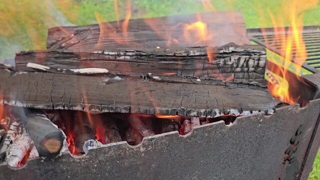 Setting fire to wood in a barbecue grill outdoors on a sunny day