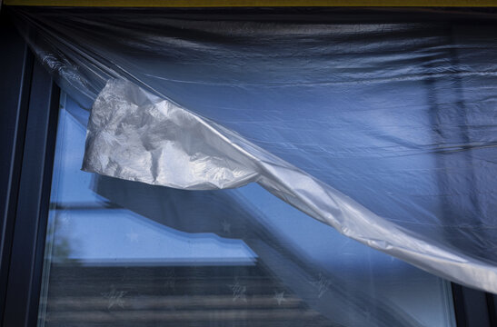 Protective plastic sheeting is unrolling in front of a window