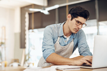 Obraz premium Manager, man and laptop for cafe inventory, process supplier order and review delivery info. Small business, waiter and glasses with tech for coffee shop admin, update menu or check restaurant rating
