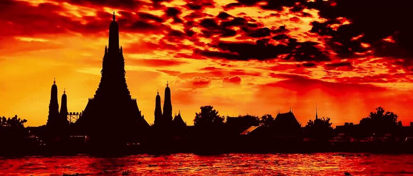  Silhouette of Wat Arun during a dramatic golden sunset over the Chao Phraya River in Bangkok, Thailand. Majestic temple structure framed by vibrant orange clouds and serene waters.