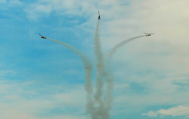 Three helicopters performing aerobatic flight with smoke trails at an airshow © DoMinh