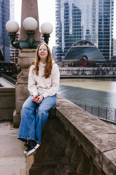 Smiling woman sits on a ledge by the Chicago River