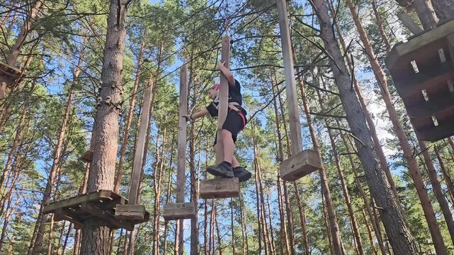 Jumping between tree platforms in a forest adventure park during a sunny day