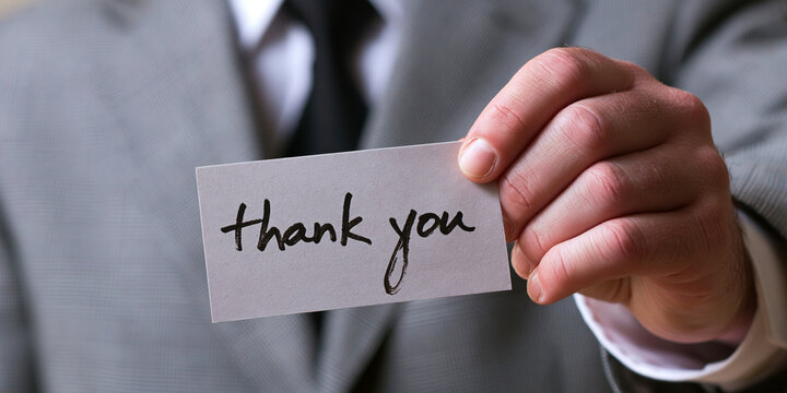 A businessman holding a card with thank you written on it