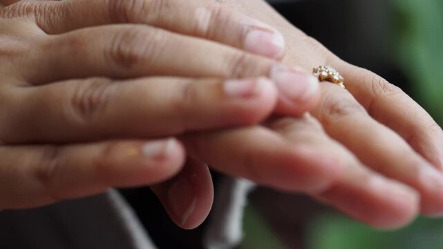 A close-up shot of a woman's hands as she applies a hydrating and soothing cream to her dry and tired skin, showing the gentle rubbing and moisturizing motion