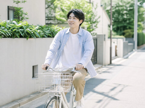天気の良い屋外で自転車を押しながら笑顔で歩く男性