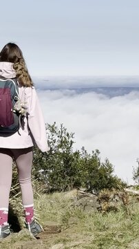 A girl walks and admires the view from the summit, with thick clouds emerging above the eucalyptus bush and a clearing, Mount Macedon, Macedon Ranges, near Melbourne, Victoria, Australia.