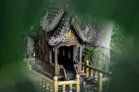 old spirit house situated beneath a tree.