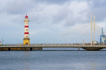 Fototapeta premium Iconic striped lighthouse stands tall beside a modern cable-stayed bridge. Malmo