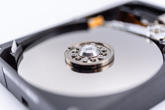 Open hard disk drive showing reflective magnetic platter spindle internal components representing computer data storage hardware technology backup information security