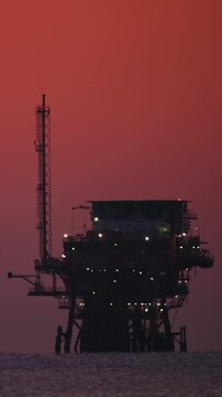 Sunset oil rig silhouette by coast