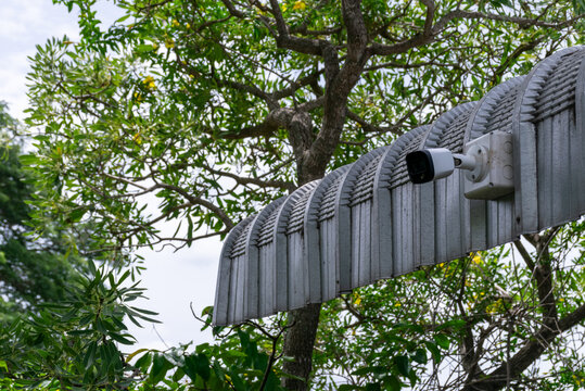 Outdoor surveillance camera mounted property entrance structure surrounded by green trees for home security monitoring safety protection access control
