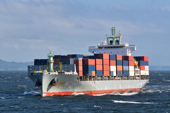 Container ship sailing on rough seas with stacked cargo containers