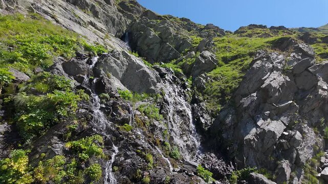 Rocky mountain waterfall surrounded by green vegetation near the Transfagarasan in the Carpathians