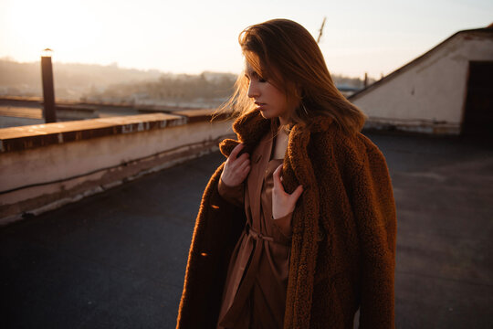 Woman in a cozy teddy coat enjoying a golden hour sunset on a rooftop