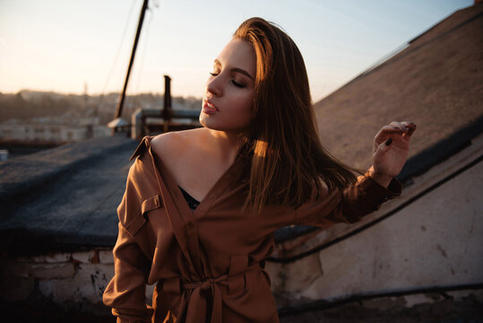 Young woman enjoying the golden hour light on a rooftop at sunset