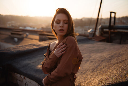 Young woman in stylish outfit enjoying a warm autumn sunset on a rooftop