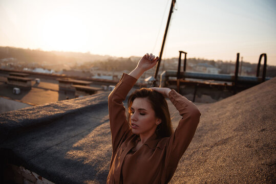 Young woman posing on a rooftop during a golden hour autumn sunset