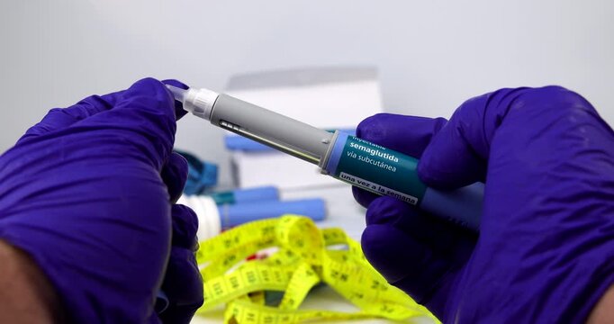 Gloved hands adjust and prepare a GLP-1 semaglutide diabetes and weight loss auto-injector pen device for subcutaneous administration over a bright white surface, illustrating medical procedure