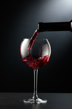Pouring red wine into a wine glass.
