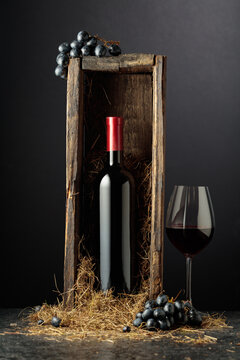 Bottle of red wine in old wooden box on a black background.