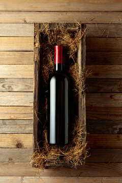 Bottle of red wine in an antique wooden box with hay.